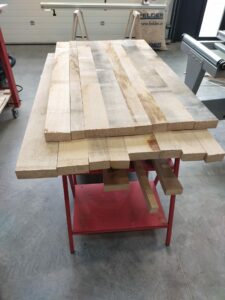 Planches de bois massif disposées sur l'établi avant découpe, atelier de Lyon