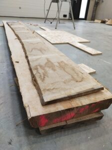 Planches de bois massif brut en attente de transformation dans l'atelier Paul de Bazelaire